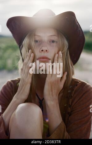 Nahaufnahme der Hippie-Frau im Cowboyhut bei Sonnenuntergang auf der Wiese. Stockfoto