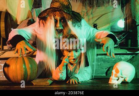 Vater und Sohn spielen Halloween. Sohn und Vater mit Kürbissen für Halloween schnitzen. Papa und sein Kind in Faschingskostümen auf Halloween Hintergrund. Stockfoto