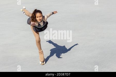 Braunhäutig Teenager-Mädchen Durchführung einer Eiskunstlauf auf Rädern. Taubenfigur Stockfoto