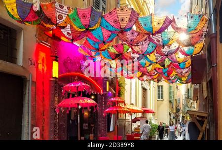 Touristen passieren unter einem bunten Sonnenschirm vor einem Geschäft in der Altstadt von Nizza Frankreich, an der Cote d'Azur. Stockfoto