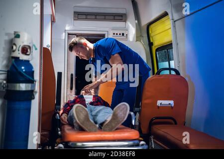 Ein Arzt in blauer Uniform gibt einer aus dem Feuer geretteten Frau eine Sauerstoffmaske. Stockfoto