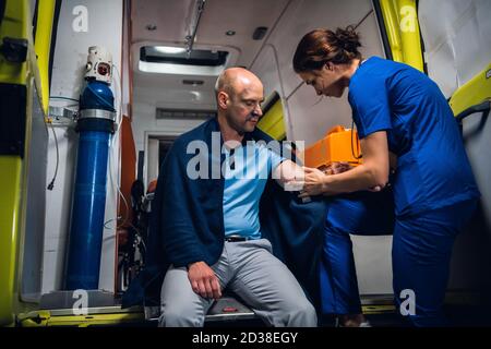 Verletzte Mann in einer Decke bekommt erste Hilfe in einem Krankenwagen. Stockfoto