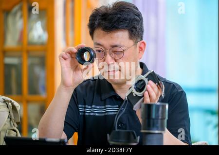 Ein asiatischer Mann mittleren Alters, dessen Hobby 35mm/135mm Film SLR-Kamera ist. Stockfoto