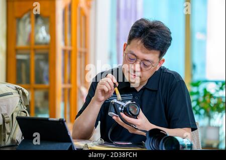 Ein asiatischer Mann mittleren Alters, dessen Hobby 35mm/135mm Film SLR-Kamera ist. Stockfoto