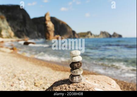 Seeigel Muscheln stehen harmonisch auf Felsen gestapelt gegen eine wunderschöne Seeslandschaft mit azurblauem Wasser und hohen Felsen, selektiver Fokus Stockfoto