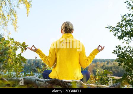 Schöne junge Mädchen meditieren im Herbst Park. Frau meditiert im Wald an sonnigen Tag. Stockfoto