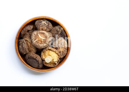 Getrocknete Shiitake-Pilze in Holzschüssel auf weißem Hintergrund. Stockfoto