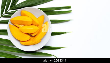 Mangoscheiben auf weißem Teller auf tropischen Palmblättern. Draufsicht Stockfoto