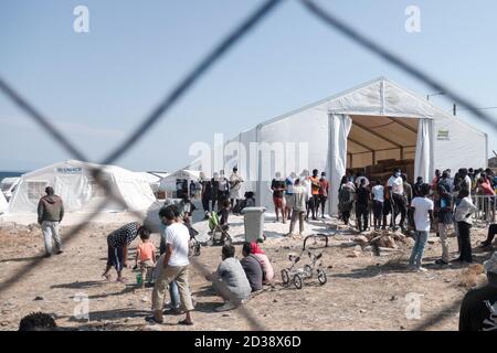 Mytilene, Insel Lesbos, Griechenland. September 2020. Asylsuchende warten in einer Schlange auf Vorräte aus einem UNHCR-Zelt.die nach dem Brand in Moria erbauten Karatepe- oder Mavrovouni-Flüchtlingslager beherbergen Flüchtlinge und Migranten, Asylsuchende, die alle vor der Einreise auf COVID-19 getestet wurden und Unterkunft und Nahrung bieten. Die Anlage wurde von der griechischen Regierung, der griechischen Armee, dem UNHCR und der Europäischen Union errichtet. Kredit: Nik Oiko/SOPA Images/ZUMA Wire/Alamy Live Nachrichten Stockfoto