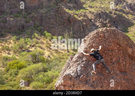 Junger Mann boulders auf einem Felsen in der Superstition Wilderness Wüste in den Superstition Mountains in der Nähe von Apache Junction, Arizona, USA Stockfoto