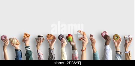 Die Menschen halten verschiedene Desserts in ihren Händen. Das Konzept von Lebensmitteln und Süßigkeiten. Stockfoto