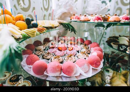 Verschiedene farbige leckere Süßigkeiten auf dem Tisch in einer Süßigkeitenbar bei einer Hochzeit. Köstliche Süßigkeiten auf Hochzeit Süßigkeiten Buffet mit Desserts, Cupcakes. Sweet Tab Stockfoto