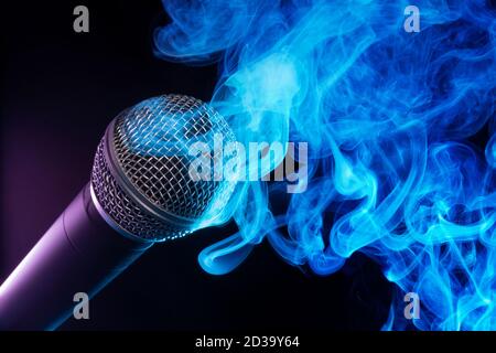 Mikrofon und blauer Rauch wirbeln auf schwarzem Hintergrund Stockfoto