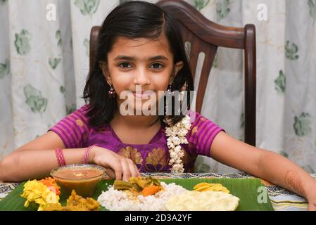 Kerala Onam Festival, glücklich indisches Mädchen Kind Essen Onam sadhya mit Hand tragen traditionelle Kleidung, Indien. Lächelndes junges asiatisches Kind. Schönes Kind Stockfoto