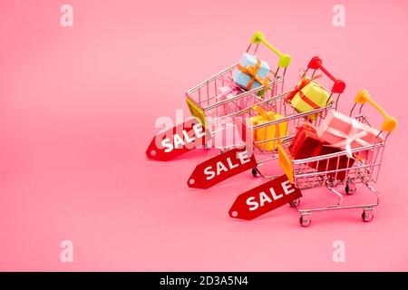 Bunte Geschenke in Warenkörben mit Sale-Tags auf pink, schwarz friday-Konzept Stockfoto
