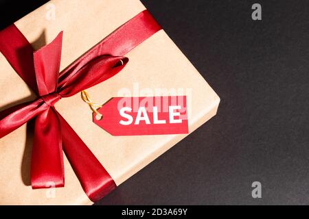 Draufsicht auf Geschenkbox mit Band und Sale-Tag auf dunklem Hintergrund, schwarz freitag Konzept Stockfoto