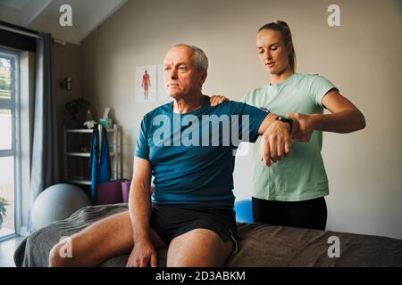 Therapeut untersucht ältere Patienten Schulter im Sprechzimmer oder Rehabilitation Klinik Stockfoto