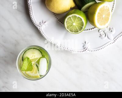 Hausgemachte Limonade aus Zitrone, Limette und Gurke auf weißem Teller und Marmortisch. Overhead-Ansicht. Stockfoto