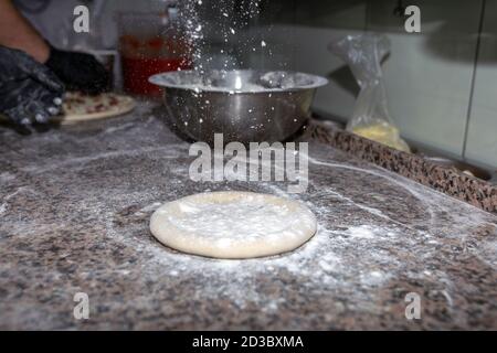 Pizzateig auf bemehlter Schieferfläche ausrollen Stockfoto