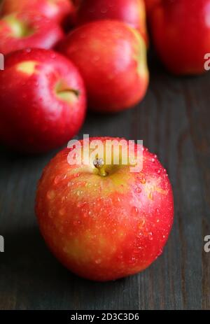 Closeup frische reife Äpfel mit Wassertröpfchen isoliert auf schwarz Holztisch Stockfoto