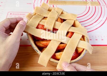 Handweben Stücke von geschnittenen Teig auf Tortenplatte für Gitterdecke Kruste eines hausgemachten Apfelkuchen Stockfoto