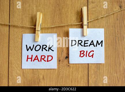 Hölzerne Wäscheklammern mit weißen Blatt Papier. Text: „Work hard, Dream big“. Schöner Holzhintergrund. Geschäftskonzept, Kopierbereich. Stockfoto