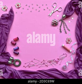 Ein Vogelperspektive Flatlay von Nähzubehör mit Baumwolle, Scheren, applique Patches, Haken und Ösen Verschlüsse, Pins und Knöpfe auf einem rosa Hintergrund. Stockfoto