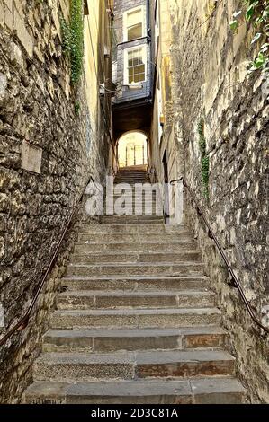 Enge alte Steintreppen, die unter einem überdachten Torbogen-Tunnel in der historischen englischen Stadt Bath vorbeiführen. Stockfoto