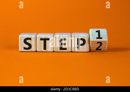 Schritt für Schritt. Einen Würfel gedreht und den Ausdruck 'step 1' in 'step 2' geändert. Schöner orangefarbener Hintergrund. Geschäftskonzept. Speicherplatz kopieren. Stockfoto