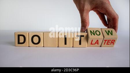 Männliche Hand dreht einen Würfel und ändert den Ausdruck 'Do it later' in 'Do it now'. Schöner weißer Hintergrund. Geschäftskonzept. Speicherplatz kopieren. Stockfoto