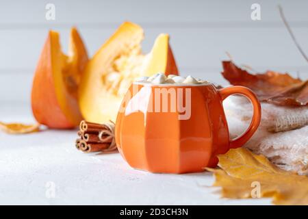 Komposition mit orangefarbenem Kürbis-Stil Tasse Kaffee mit Marshmallows und Herbstdeko, gefallenen Blättern, gemütlichem Pullover auf weißem Hintergrund. Stockfoto