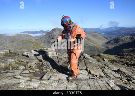 Veteran Fundraiser Lloyd Scott, der versucht, die Three Peaks zu besteigen, um Lord's Taverners Wohltätigkeitsorganisation zu helfen, während er einen Tiefseetauchanzug trägt, während seiner Herausforderung auf Scafell Pike, im Lake District National Park, in Cumbria. Stockfoto