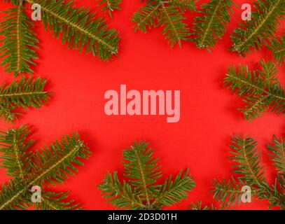 Weihnachten flach legen mit Tannenzweigen Rahmen auf einem roten Hintergrund und kopieren Raum innen. Stock Foto. Stockfoto
