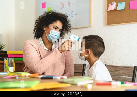 Lehrerin Frau Check-up Temperatur auf Kind im Klassenzimmer während Corona Viruspandemie - Gesundheitsmedizin und Bildungskonzept Stockfoto