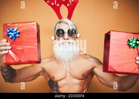 Happy fit Senior hält Weihnachtsgeschenke - Hipster älterer Mann Mit Spaß geben Geschenk-Box während der Weihnachtsferien Stockfoto