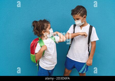 Kinder tragen Gesichtsschutzmaske gehen zurück zur Schule während corona Virus Pandemie - kleine Kinder tun neue soziale Distanz Grußansage mit anstoßenden Ellbogen Stockfoto