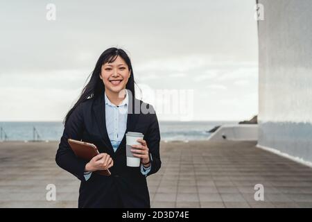 Asiatische Geschäftsfrau hält intelligente Tablette und trinken mitnehmen Kaffee außerhalb Büro - Entrepreneurship professionelle Job-Konzept Stockfoto