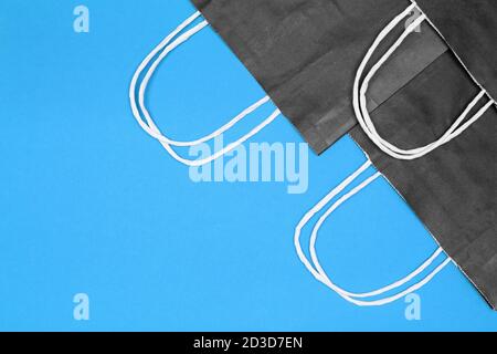 Schwarze Kraftpapier Merchandise Taschen auf blauem Hintergrund. Speicherplatz kopieren. Shopping, Verkauf minimales Konzept Stockfoto