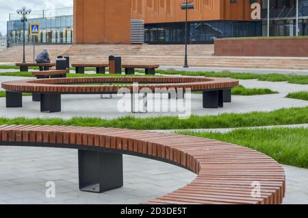 Kasan, Russland, 16. September 2020. Runde Holzbänke vor dem Eingang zu einem modernen Gebäude. Platz in der Nähe des Kazan Millennium Museums Stockfoto