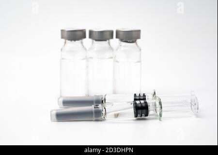 Impfkonzept mit Spritze und Fläschchen auf weißem Hintergrund. Stockfoto