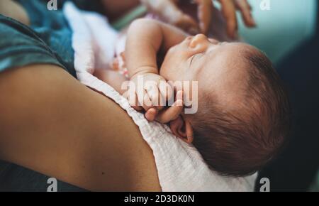 Kleines kaukasisches Baby schläft, während seine Mutter ihn hält In den Armen Stockfoto