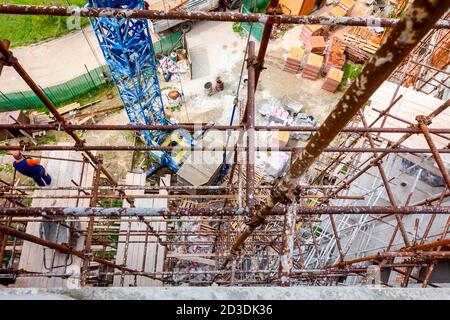 Das Gerüst wird gegen das Gebäude gestellt. Chef wird von der Holzplattform über der Baustelle beaufsichtigt. Stockfoto