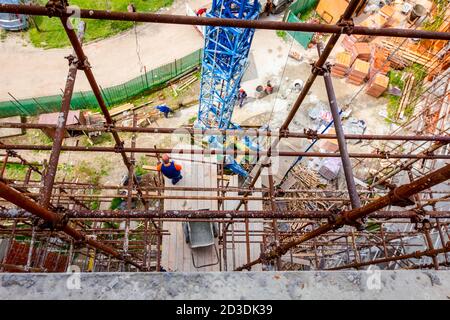 Das Gerüst wird gegen das Gebäude gestellt. Chef wird von der Holzplattform über der Baustelle beaufsichtigt. Stockfoto