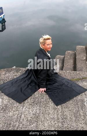 Weiß kaukasisch gefärbte blonde Frau mittleren Alters in ihren 40er Jahren trägt eine Lederjacke aus einem Second-Hand-Shop gekauft. Sie läuft um den Hafen herum und sieht nachdenklich aus Stockfoto