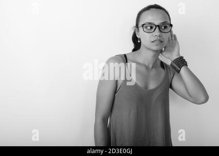 Studio-Aufnahme der jungen asiatischen Frau denken beim Zuhören und Brillen auf weißem Hintergrund Stockfoto
