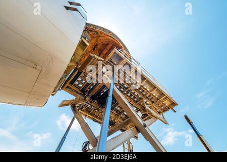 Ein Jumbo Jet-Frachter mit einer weit geöffneten Nase Ladetür, die von einem Hochlader an einer Laderampe, von unten gesehen, abgeladen wird Stockfoto