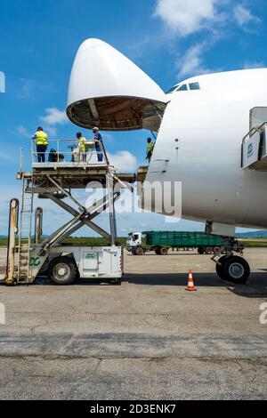 Eine Boeing B747 Jumbo Jet Frachter Flugzeug mit einem breiten Öffnen Sie die Nasentür, die von einem Hochlader an entladen wird Eine Laderampe Stockfoto