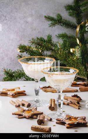 Eierlikör Weihnachten Milch Cocktail, in zwei vintage Crystal serviert Gläser mit SHORTBREAD Stern Sugar Cookies, Zimtstangen, tanne Zweig über Weiß Stockfoto