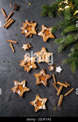 Hausgemachte Weihnachten neues Jahr Stern Zucker karamel Kekse mit Zuckerguss und orange Zitrus Marmelade, Zimtstangen und Anis über schwarzen Textur backgro Stockfoto