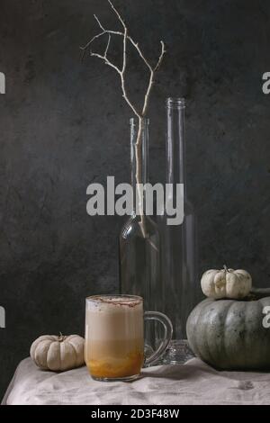 Glas Kürbis layered Spice Latte mit kürbispüree, Milchschaum und Zimt stehend mit Flaschen, Niederlassung, dekorativen weißen Kürbisse auf zerknitterte t Stockfoto